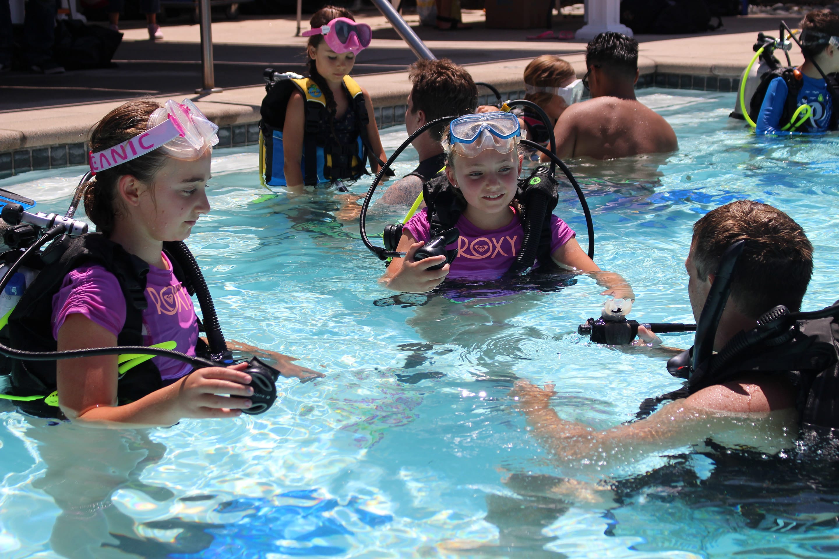First-time scuba students practicing with instructors in a pool